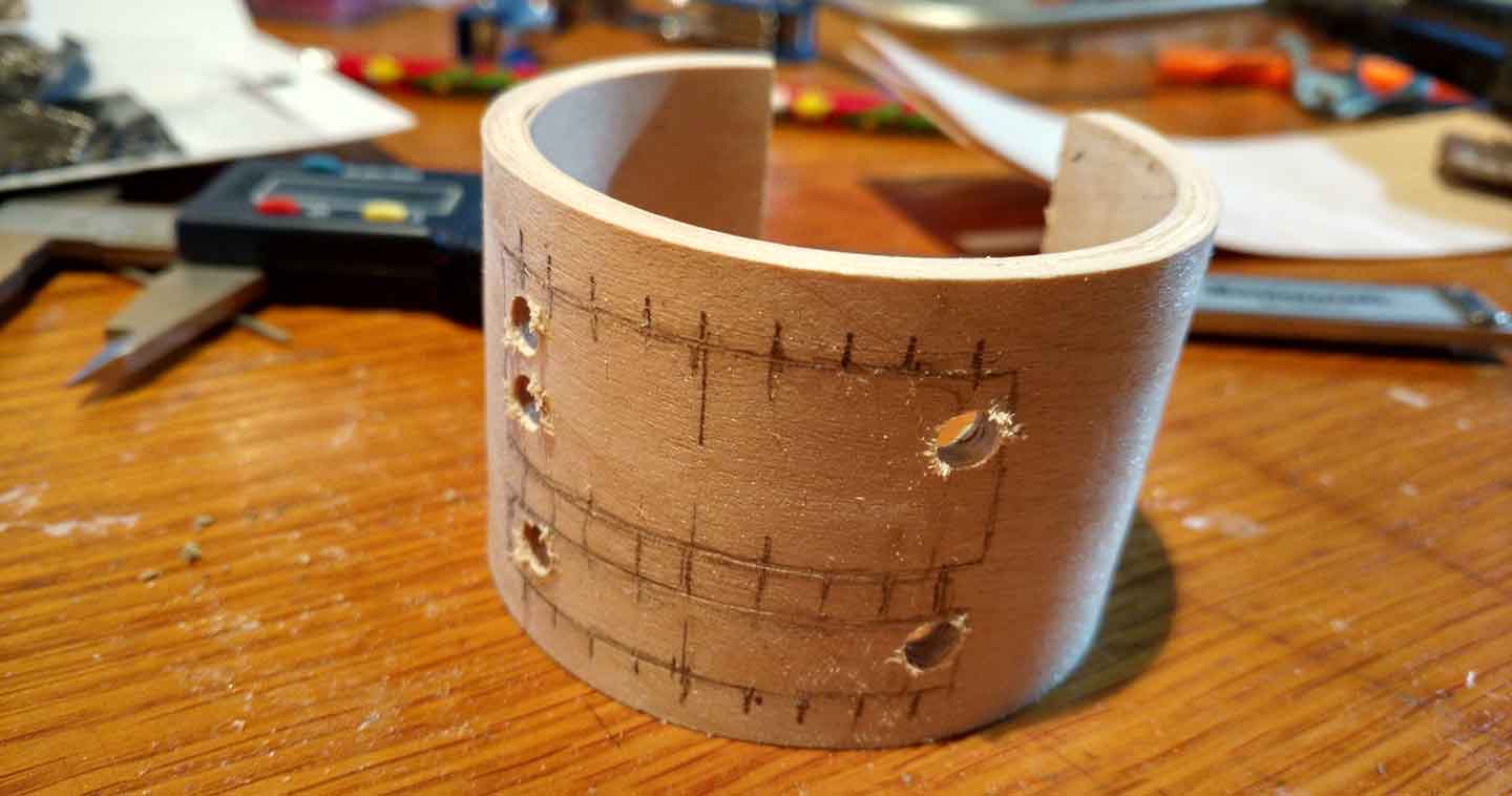 wood bracelet with holes drilled in the body to put a small saw blade through